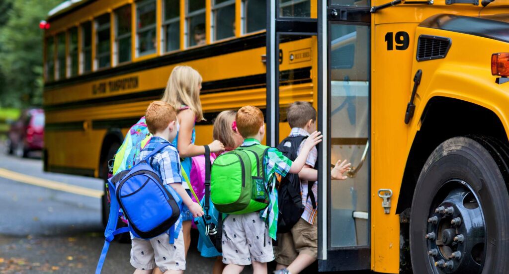 Children boarding yellow school bus.