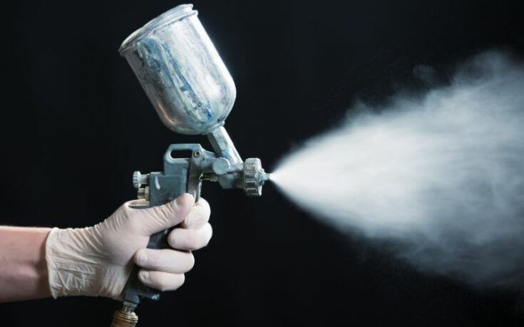 man spraying a white powder coating